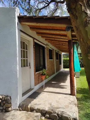 a white house with a wooden pergola at Cabañas del IntiCo in Arroyo de Los Patos