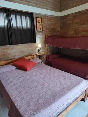 a bedroom with two beds and a brick wall at Cabañas del IntiCo in Arroyo de Los Patos