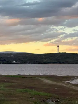 a large body of water with a lighthouse in the distance at Apartamento Carde Housing in Villa Carlos Paz