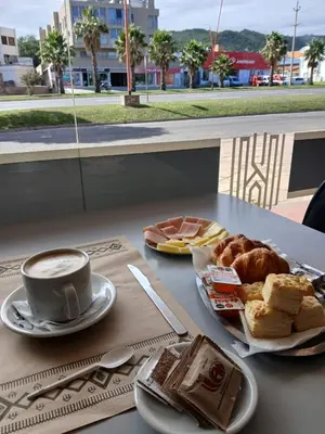 a table with a cup of coffee and a plate of pastries at KIN Hotel in Villa Carlos Paz