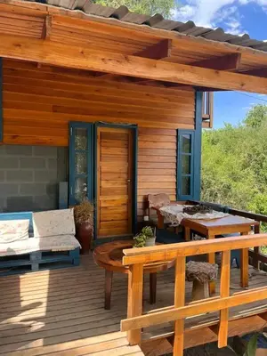 a wooden cabin with a table and a bench on a deck at Cabañas Mari-Tina in Villa Serranita