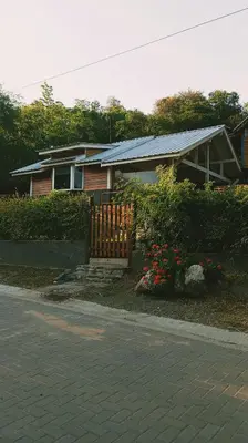 a house with a fence and flowers in front of it at Cabañas Mari-Tina in Villa Serranita