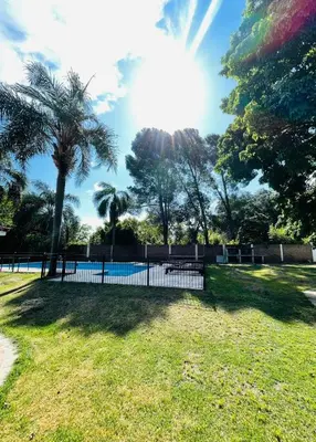 a fence with a pool in a park with a palm tree at perfecta casa en Cordoba in Cordoba