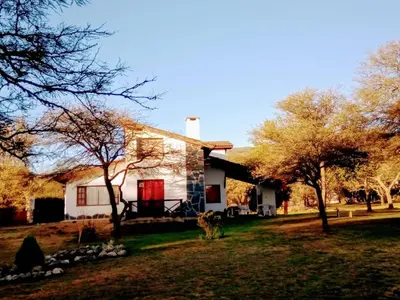 a white house with trees in front of it at Cabañas Rey Garcia in Villa General Belgrano