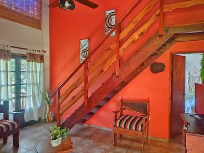 a living room with orange walls and a staircase at Cabañas Rey Garcia in Villa General Belgrano