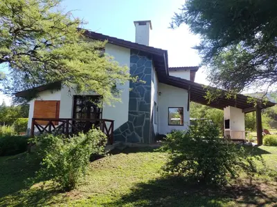 a house with a stone facade and trees at Cabañas Rey Garcia in Villa General Belgrano