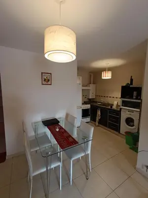 a kitchen with a glass table and white chairs at Departamento Nuevo centro shopping in Cordoba