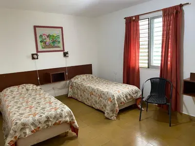 a bedroom with two beds and a chair and a window at CastelAnte1 in Villa Carlos Paz