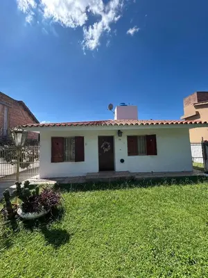 a white house with a fence in a yard at Casa Jazmín in Villa Carlos Paz