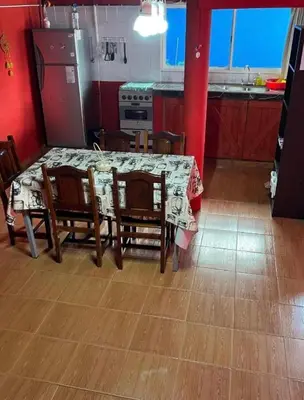 a kitchen with a table and chairs and a kitchen with red walls at La Morada in Mina Clavero