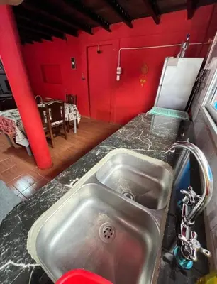 a kitchen with a sink and a red wall at La Morada in Mina Clavero