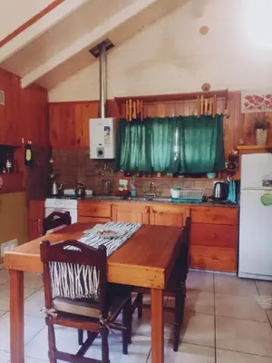 a kitchen with a wooden table and a white refrigerator at Cabañas Mari-Tina in Villa Serranita