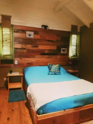 a bedroom with a bed with a wooden wall at Cabañas Mari-Tina in Villa Serranita