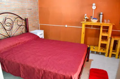 a bedroom with a red bed and a wooden wall at Complejo Fresia in Mina Clavero