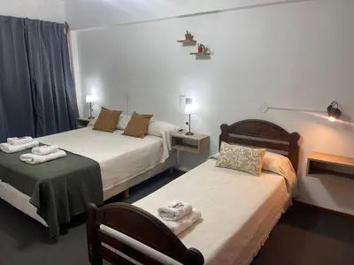 a hotel room with two beds and a chair at Hotel Palo Verde in Mina Clavero