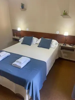 two beds in a hotel room with blue sheets and pillows at Hotel Palo Verde in Mina Clavero