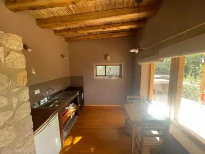 a kitchen with a sink and a table with chairs at Cabaña Peperina in San Javier