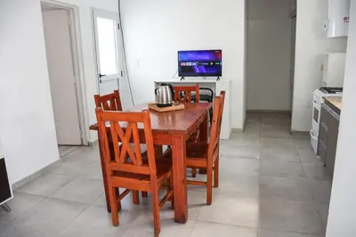 a kitchen with a wooden table with chairs and a television at Rio Segundo Colo 2 in Río Segundo