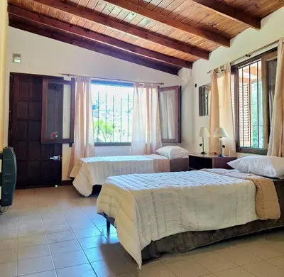 a bedroom with two beds and a large window at Chalet con puerta al arroyo in Villa General Belgrano