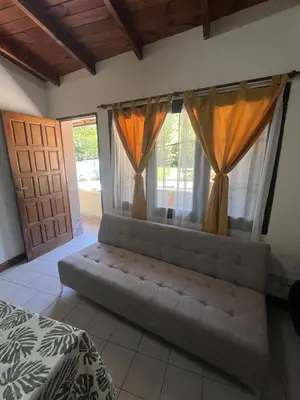 a bedroom with a couch in front of two windows at Chalet con puerta al arroyo in Villa General Belgrano