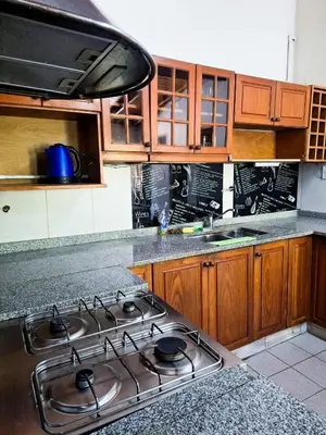 a kitchen with a stove top and wooden cabinets at Chalet con puerta al arroyo in Villa General Belgrano