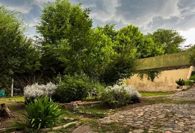 a garden with a stone path and trees at Chalet con puerta al arroyo in Villa General Belgrano