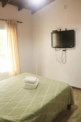 a bedroom with a bed with a flat screen tv on the wall at Quiya ná in Cortaderas