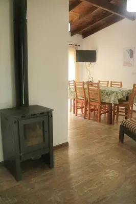 a living room with a stove and a table and chairs at Quiya ná in Cortaderas