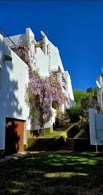 a building with purple flowers on the side of it at Apartamento con bajada al lago Aldea del Puente in Villa Carlos Paz