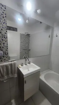 a bathroom with a sink and a tub and a mirror at Apartamento con bajada al lago Aldea del Puente in Villa Carlos Paz