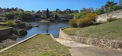 a river with a retaining wall next to a city at Apartamento con bajada al lago Aldea del Puente in Villa Carlos Paz