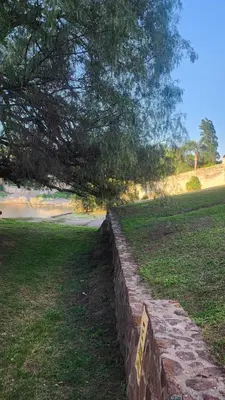 a stone wall in a field with a sign on it at Apartamento con bajada al lago Aldea del Puente in Villa Carlos Paz