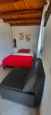 a bedroom with a red bed and a black couch at CabañaPaz in Santa Rosa de Calamuchita