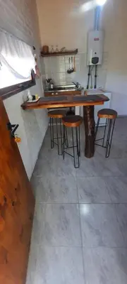 a kitchen with a table and stools in a room at CabañaPaz in Santa Rosa de Calamuchita