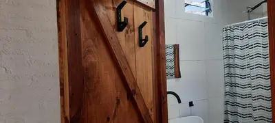 a wooden door in a bathroom with a toilet at CabañaPaz in Santa Rosa de Calamuchita