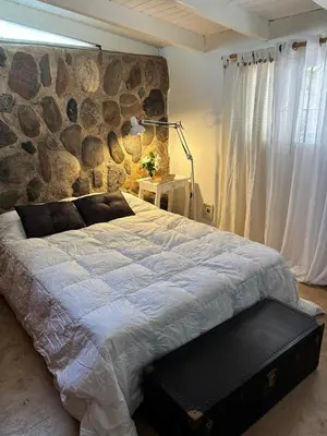a bedroom with a large bed with a stone wall at Casa Campo La Carolina in Cordoba