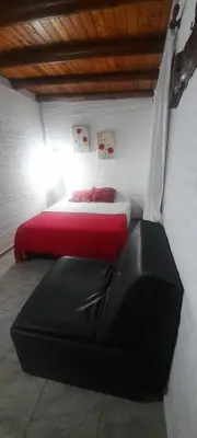 a bedroom with a bed and a black leather couch at Cabaña Paz in Santa Rosa de Calamuchita