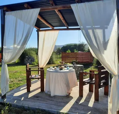 a table and chairs under a pavilion with white curtains at Cabaña Paz in Santa Rosa de Calamuchita