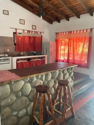 a kitchen with a stone counter and two stools at Cabañas Doña Chicha - San Clemente, Córdoba in San Clemente