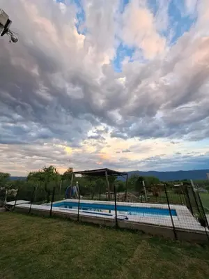 a swimming pool with a gazebo next to a field at Cabaña la Fride in Cosquín