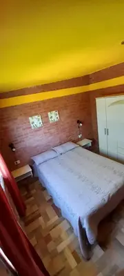 a bedroom with a large bed with a yellow wall at Departamentos Las Marias in Villa Cura Brochero