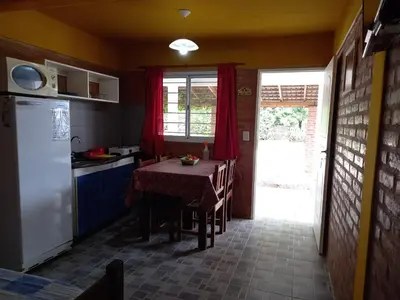 a small kitchen with a table and a refrigerator at Departamentos Las Marias in Villa Cura Brochero