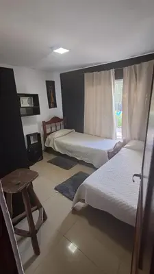 a bedroom with two beds and a table and a window at Mi casita en Embalse in Embalse
