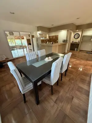 a dining room with a black table and white chairs at Los viejos Potrero de Garay in Villa Anizacate