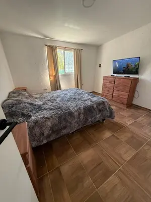 a bedroom with a large bed and a flat screen tv at Los viejos Potrero de Garay in Villa Anizacate