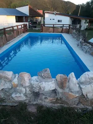 a swimming pool with blue water and rocks around it at Ikigai alojamiento con piscina in Villa Rumipal