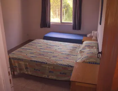 a small bedroom with a bed and a window at Ikigai alojamiento con piscina in Villa Rumipal