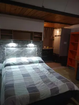 a bedroom with a large bed with a stone wall at Ikigai alojamiento con piscina in Villa Rumipal