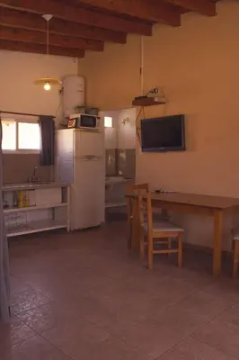 a kitchen with a table and a white refrigerator at Ikigai alojamiento con piscina in Villa Rumipal