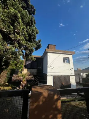 a white house with a fence in front of it at Departamento Santa rita in Villa Carlos Paz
